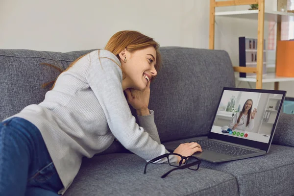 Frau im Gespräch mit Arzt online mit Laptop-Computer zu Hause. Junge Patientin konsultiert ihren Therapeuten per Internet — Stockfoto