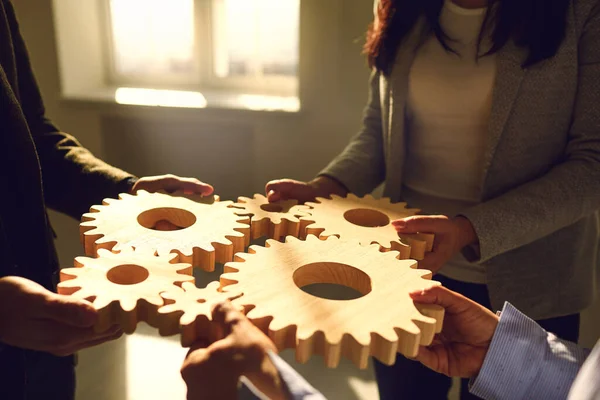 Zakenmensen die houten tandwielen in hun handen hebben maken verbinding op een zakelijke bijeenkomst in het kantoor. — Stockfoto