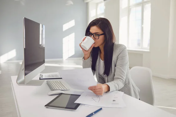 Affärskvinna i glasögon självsäker sittande vid ett bord på arbetsplatsen på kontoret — Stockfoto