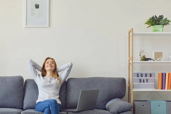 Girl have hands behind her head resting in a pause after work sitting on a sofa indoors at home. — Stock Photo, Image