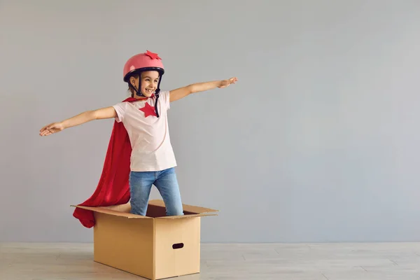 Petite fille super héros volant en boîte sur fond gris — Photo