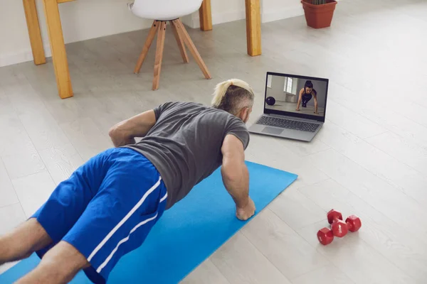 Спортивные упражнения дома с помощью ноутбука видео-чата в гостиной . — стоковое фото