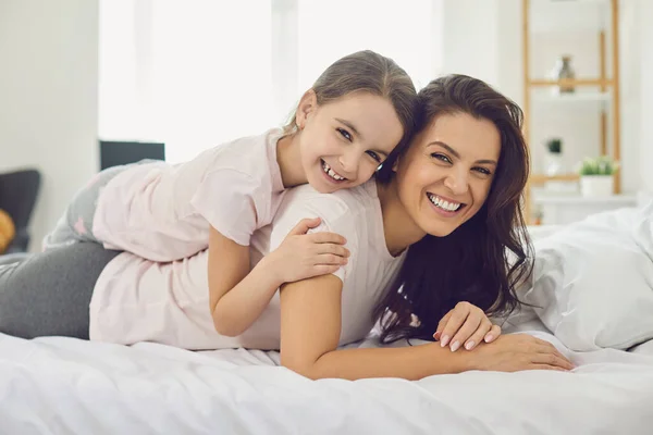 Glücklicher MuttertagPortrait von glücklicher Mutter und Tochter, die zu Hause auf dem Bett liegen. — Stockfoto