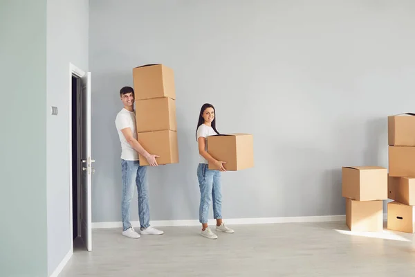 Pareja feliz con cajas de cartón abrazos de pie en una casa nueva . — Foto de Stock