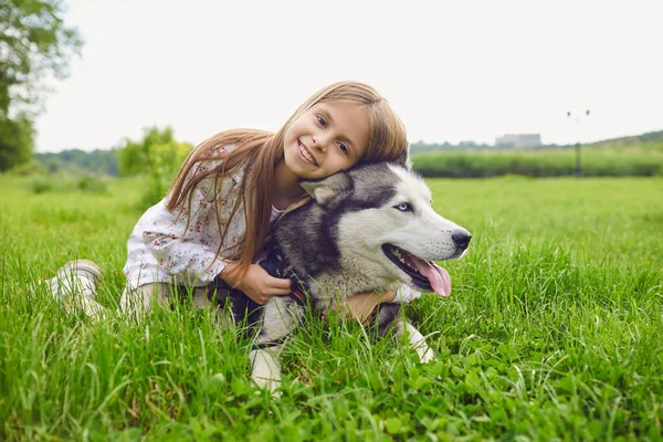 Девочка-подросток обнимает свою хаски-собаку в выходной на лугу на природе . — стоковое фото
