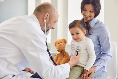 Klinikteki doktoru ziyaret eden bir aile. Steteskoplu kıdemli doktor, annesinin hastanedeki hastalarına bakan küçük bir kızı dinliyor..