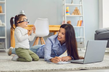 Genç bir anne dizüstü bilgisayarda çalışırken ya da çalışırken tatlı kızı evde aptalca oyunlar oynuyor. Çoklu görev kavramı