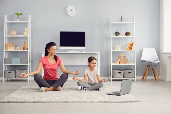 Keluarga Yoga. Ibu dan anak berlatih online kursus video yoga memiliki laptop duduk di lantai di dalam ruangan. — Stok Foto