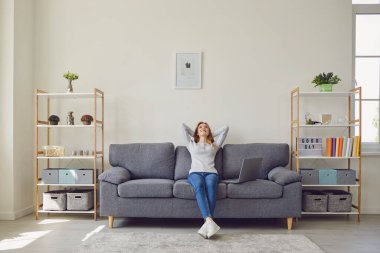 Uzaktan kumandalı iş. Dizüstü bilgisayarı olan genç ve güzel bir kadın işten izin alıp oturma odasında kanepede dinleniyor.