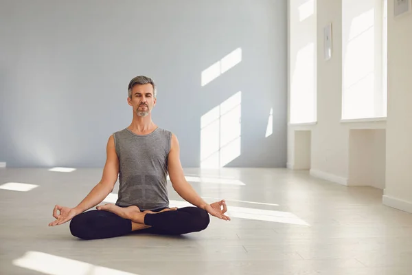 Yoga man. Bearded guy is practicing yoga in a lotus position sitting in a studio