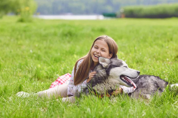 Happy little girl child with a husky dog plays in nature. — Stock Photo, Image