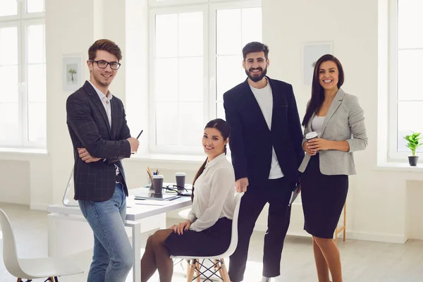 Grupp affärsmän stående ser leende stående vid ett bord på kontoret — Stockfoto