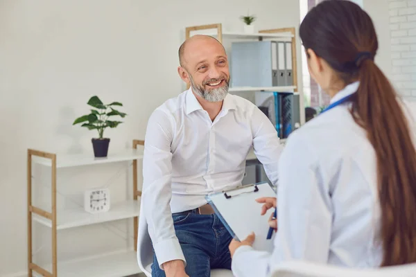 Un uomo di mezza eta 'parla con un dottore in ufficio. Consultazione medica diagnosi prescrizione in ospedale — Foto Stock