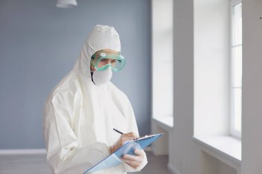 Doktor ya da tıp araştırmacısı yüz maskesi takıyor ve vücuduna pano takıyor..