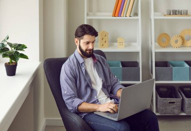 İş adamı ev ofisteki bilgisayarını uzaktan kontrol etmek için kullanıyor. Çevrimiçi bilgi için erkek yönetici internette geziniyor