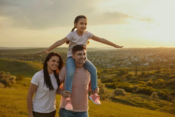 Család a természetben. Boldog fiatal család sétál vidéken naplementekor. — Stock Fotó