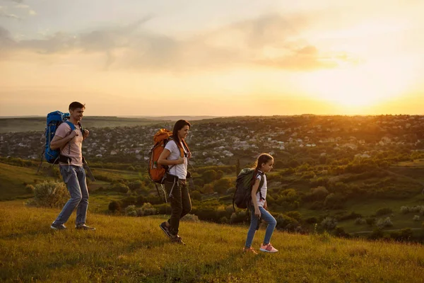 Mãe, pai e sua filhinha com mochilas caminhando juntos nas montanhas, copiar texto espaço — Fotografia de Stock