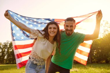 Amerikan bayrağı taşıyan bir çift parkta Amerika 'nın bağımsızlığını kutluyor..