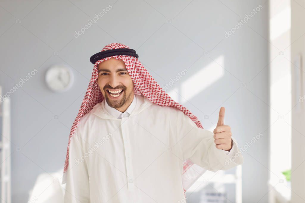 Happy arab man raised his thumb up in a white office