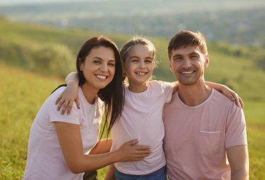 Gülümseyen aile kucaklaşması yazın doğanın arka planında.