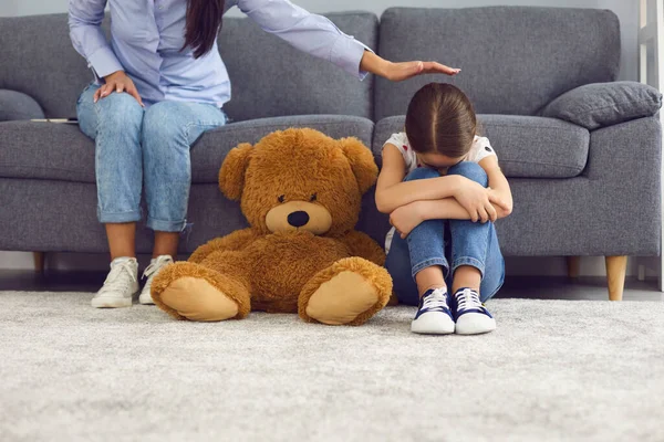 Gadis kecil yang marah menangis di lantai dekat boneka beruang sementara ibunya menghiburnya di rumah. Orangtuanya menenangkan anaknya yang tidak bahagia. — Stok Foto