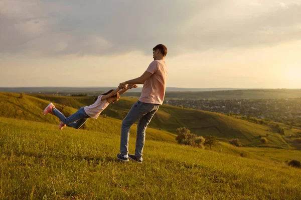 Fiatal apa játszik a lányával vidéken naplementekor, másolja le a helyet. Apa körbe-körbe forog a szabadban. — Stock Fotó