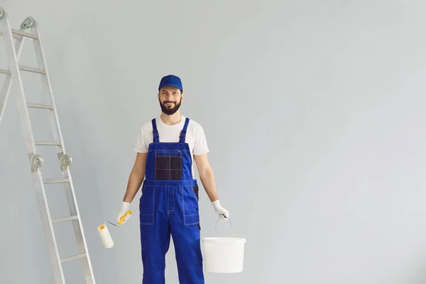 Maler hält Pinsel und Eimer mit Farbe in der Hand. — Stockfoto