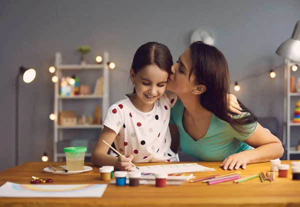Anak itu menggambar. Ibu mengajarkan anak perempuan untuk menggambar dengan cat di atas kertas duduk di meja di ruang tamu. — Stok Foto