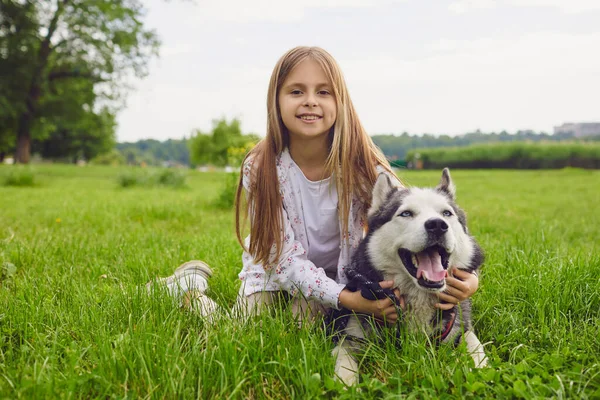 Улыбающийся ребенок с собакой Хаски играет на лугу летом весной в парке . — стоковое фото