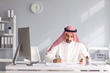 Calm arabian man sits at a table in the office. A