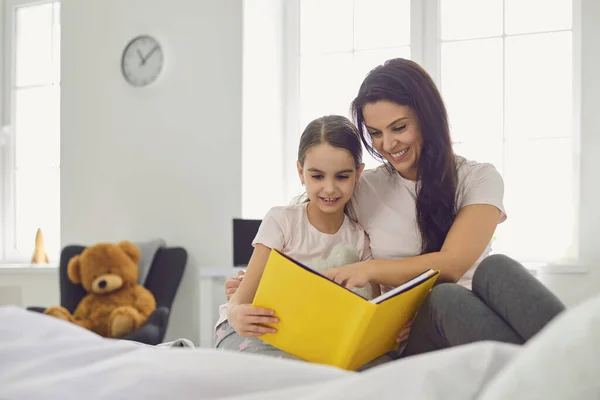 Happy Mothers Day. Mutter und Tochter lesen ein Buch, während sie zu Hause im Bett liegen. — Stockfoto