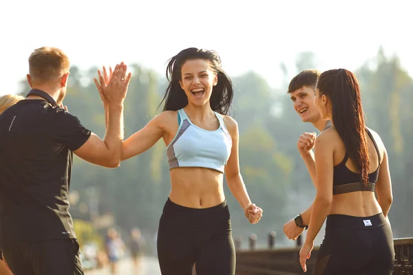 Girl runner runs fun with a group of friends in a park