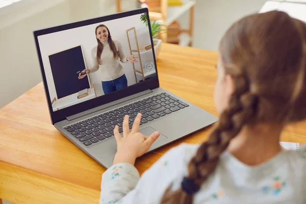 Escola de educação de aprendizagem online. Uma menina está assistindo a uma aula de vídeo. Um curso online usa um laptop enquanto está sentado em uma mesa em casa . — Fotografia de Stock