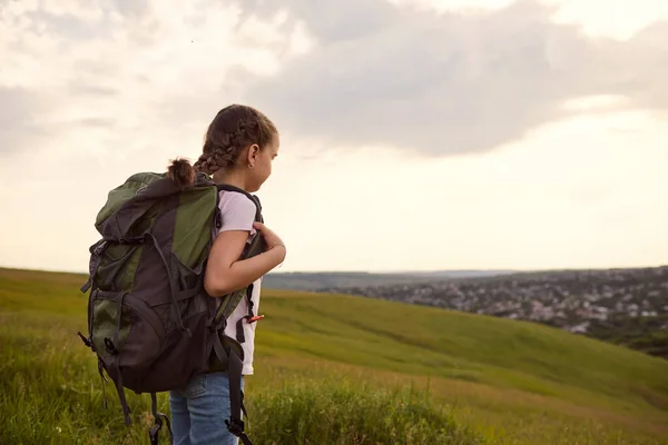 Menina turista com uma mochila em uma caminhada passeia para a frente na natureza vista traseira . — Fotografia de Stock