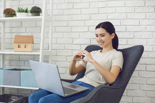 Junge Brünette chattet online und macht Herd Zeichen. Seitenansicht der Videoanrufkommunikation. — Stockfoto