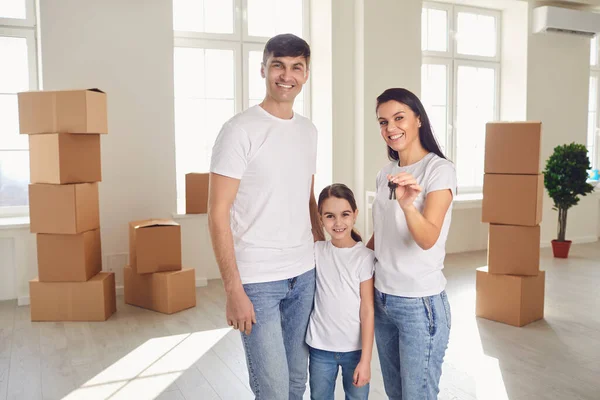 Glückliche Familie mit Schlüssel in der Hand steht in neuem Haus. — Stockfoto