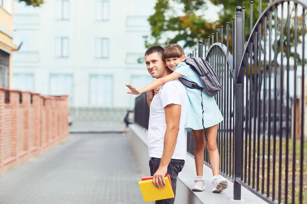 Schoolgirl with father smiling outdoors at school. — Stock Photo, Image