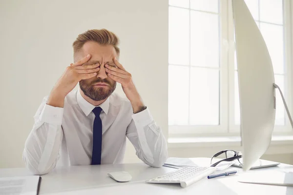 Allvarligt upptagen affärsman läser arbetsdokument sitter vid ett bord med en dator på kontoret. — Stockfoto