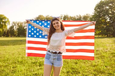 Kırsal kesimde Amerikan bayrağına sarılmış genç bir kadın. Bağımsızlık Günü