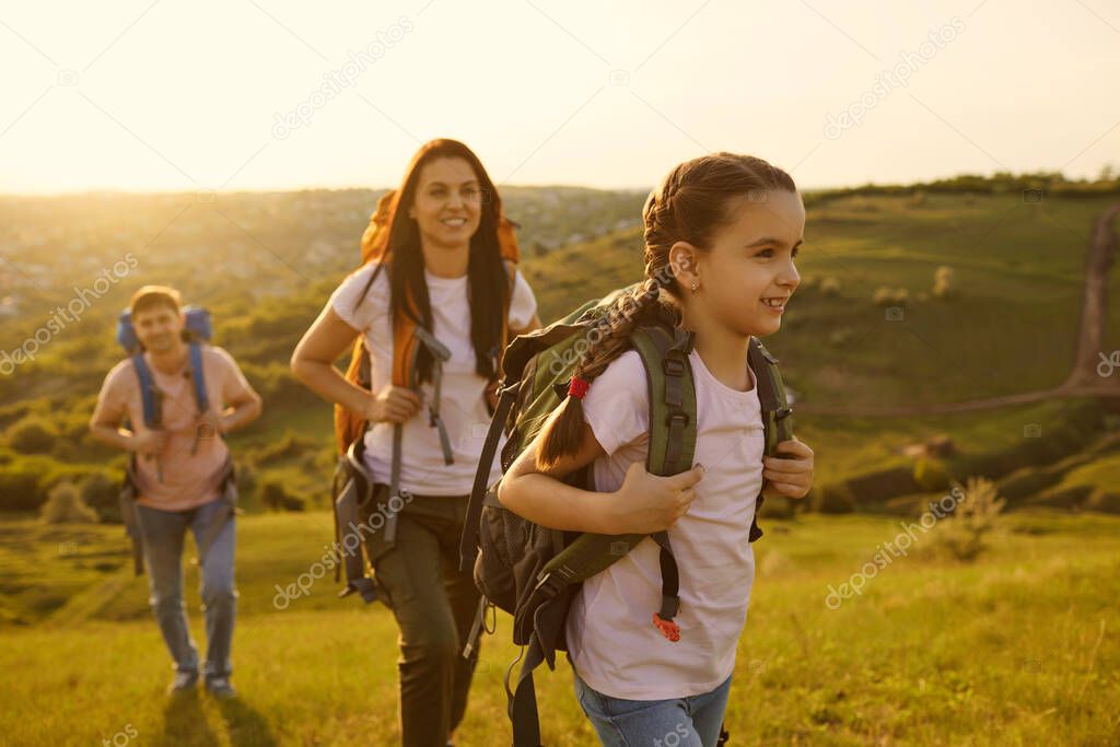 Family with a child with backpacks on a walk in nature at sunset.