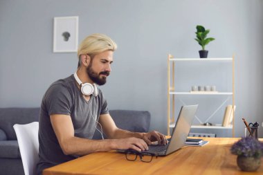 Bilgisayarlı genç adam evde çalışıyor, eğitim kursuna gidiyor ya da görüntülü sohbet yoluyla iletişim kuruyor.