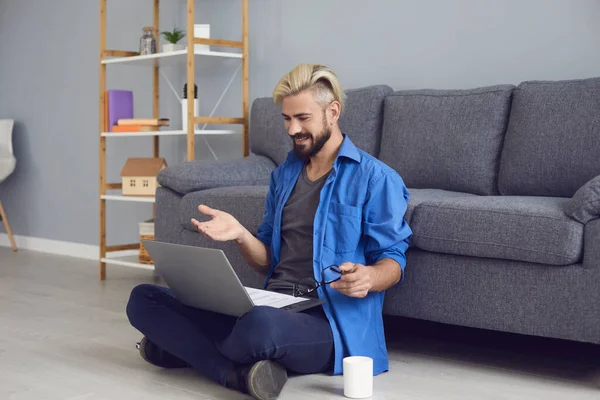 Kancelářský pracovník komunikující prostřednictvím video chatu pomocí notebooku v obývacím pokoji. Šťastný chlap pracující nebo studující online z domova — Stock fotografie