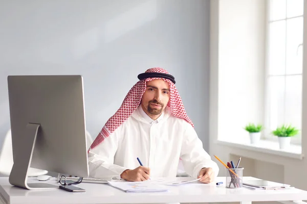 Un uomo arabo calmo siede a un tavolo in ufficio. A — Foto Stock