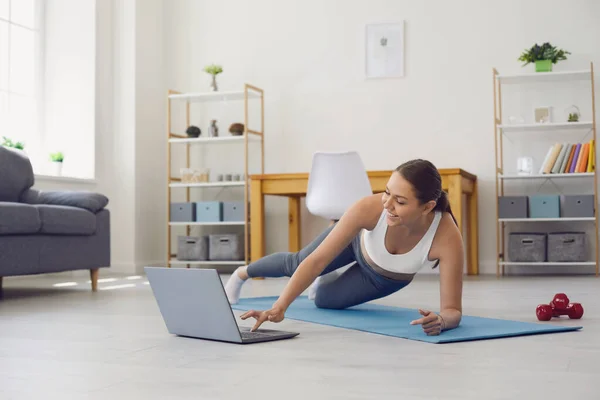 Online home fitness. Woman with laptop training to web video tutorial. Personal trainer giving yoga class via internet — Stock Photo, Image