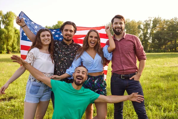 Amerika függetlenségének hazafias ünnepe július 4-én. Barátok mosolygó amerikai zászló ünneplik USA függetlenség napja — Stock Fotó
