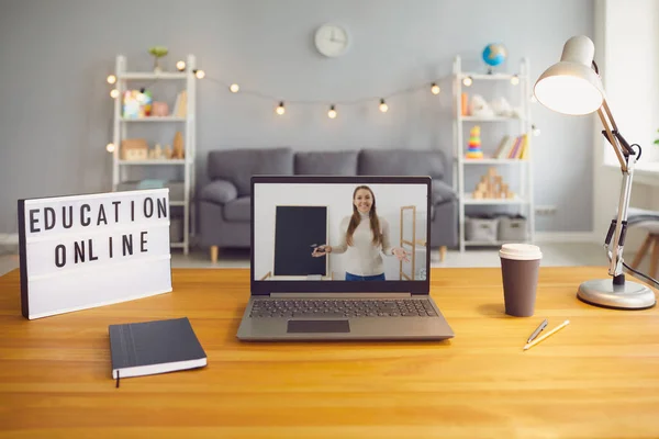 Online education. Laptop computer with young teacher giving class through webcam on screen standing on desk at home — Stock Photo, Image