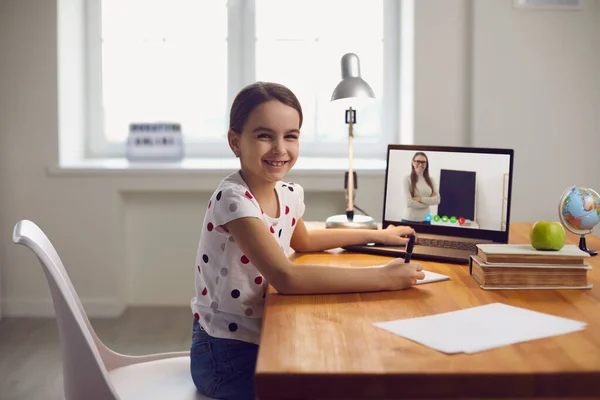 Rozmowa wideo online uczy dziecko. Mała dziewczynka robi lekcję oglądając wideo wykład nauczyciel online używa gadżet laptopa w salonie. — Zdjęcie stockowe