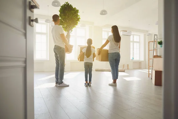 Lycklig familj med barn som flyttar med lådor i ett nytt lägenhetshus. Bakifrån. — Stockfoto