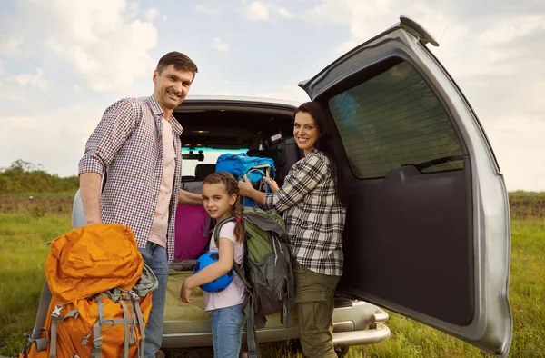 Smiling family of travelers by car standing in nature in summer. — Stock Photo, Image