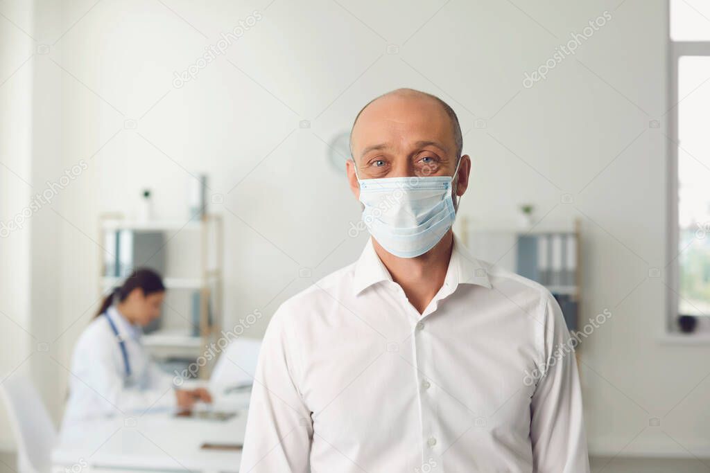 Senior man wearing protective mask on visit to doctor at hospital, blank space. Patient and medical specialist at clinic